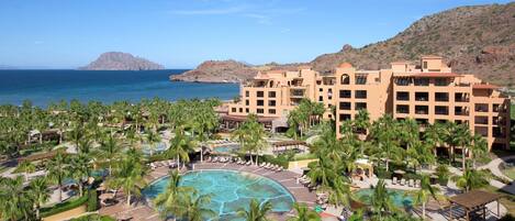 A resort with multiple buildings, a central pool area, and palm trees.