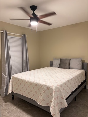 A bedroom with a bed, curtains, a ceiling fan, and a window with blinds. - Cozy 2BR/1BA house in lovely Bradenton 25 minutes from Beaches (Bradenton)