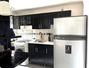 A kitchen with black cabinets, a white refrigerator, and a stove. - Apartment near the town of Medellín (Medellín)