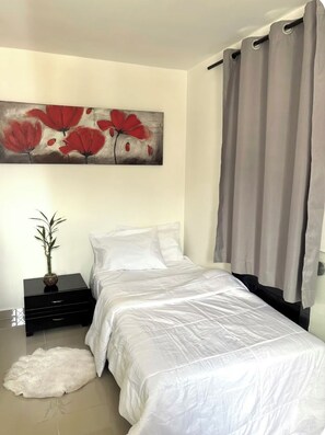 A bedroom with a bed, a nightstand, a painting, and a window with curtains. - Apartment near the town of Medellín (Medellín)