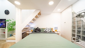 A bedroom with a bed, a TV, a plant, a staircase, and a window with a view. - Tonight Homestay South Shanxi Road Shanghai Ledu Building (SHANGHAI)