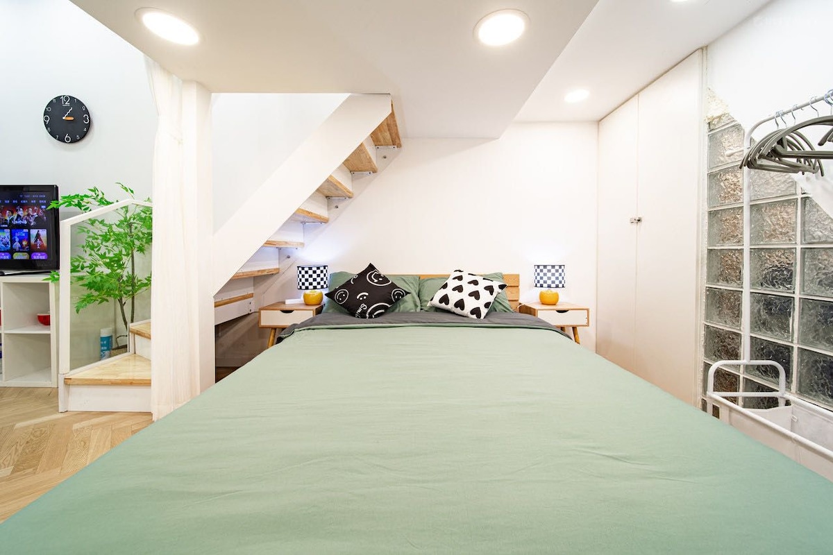 Quarto com cama, televisão, planta, escada e janela com vista.