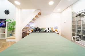 Quarto com cama, televisão, planta, escada e janela com vista.