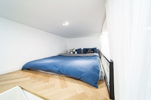 A bedroom with a bed, a desk, and a chair.