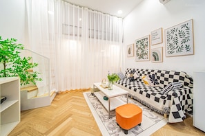Uma sala de estar moderna com um sofá estampado em xadrez, uma mesa de centro e um vaso com planta.