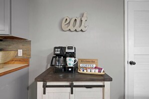 Et tekøkken med kaffemaskine, kop og et skilt der siger 'Kaffetid'.
