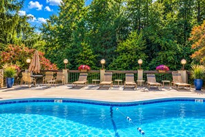 A pool area with lounge chairs and tables, surrounded by lush greenery and decorative lighting. - 2 King Suites*Close to Gatlinburg-3 mile drive! (Gatlinburg)
