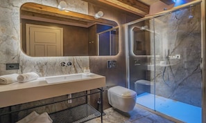 Une salle de bain moderne avec un lavabo en marbre, des toilettes et une douche à parois de verre.