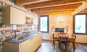 Une cuisine moderne avec un îlot central, un coin repas comprenant une table et des chaises, et un mur en pierre en arrière-plan.