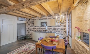 A dining area with a wooden table and purple chairs, a patterned wall, and a chandelier. - ELEGANT CORTE RUBBI 2-BEDROOM RETREAT STEPS FROM ST. MARK'S SQUARE (Venezia)