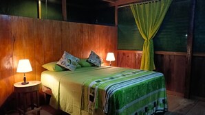 Una habitación de madera con una cama, dos lámparas de noche y una cortina.
