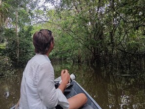 Una persona en un bote con una cámara, rodeada de abundante vegetación y agua.