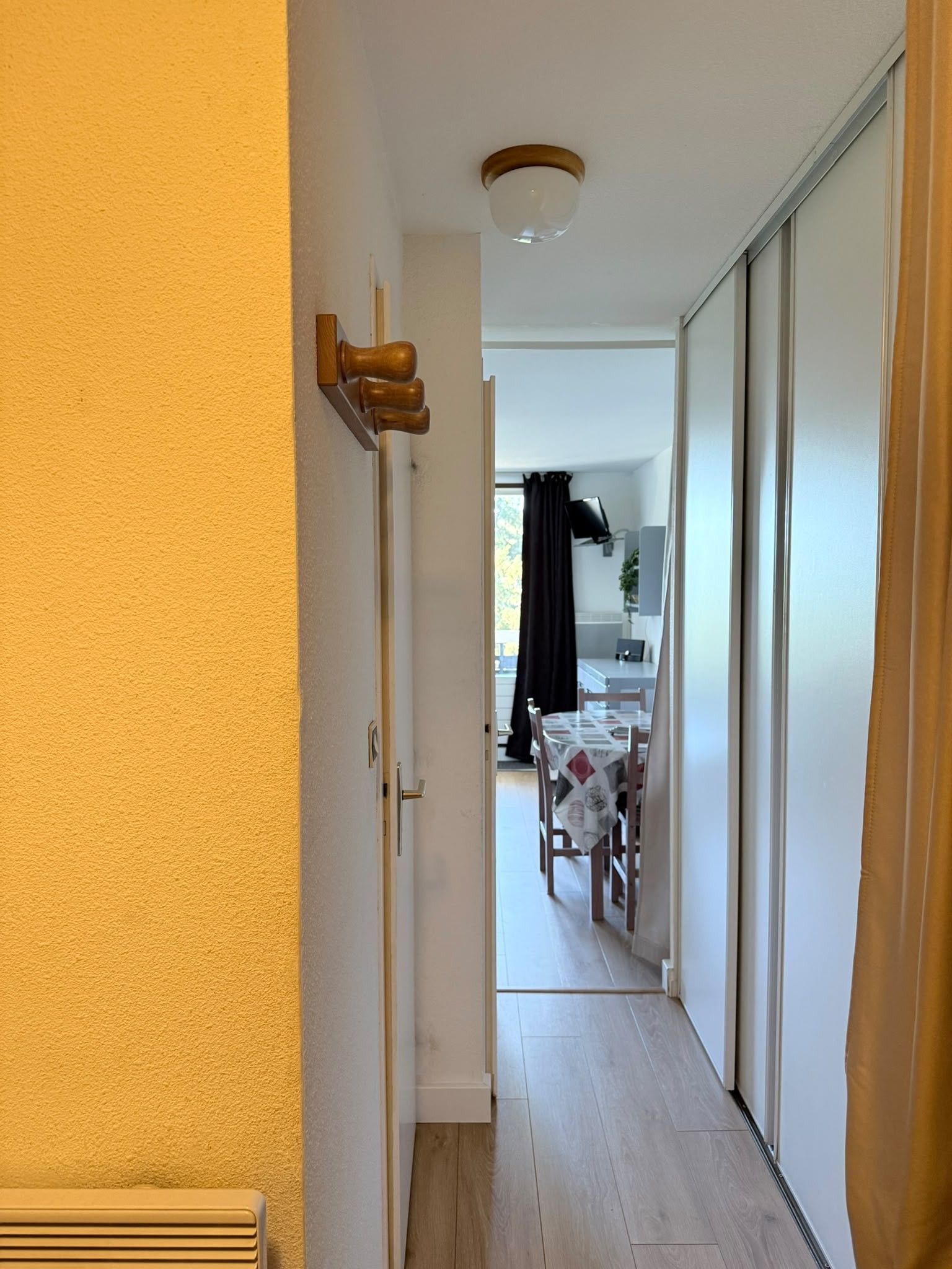 Un estrecho pasillo que conduce a un comedor con una mesa y sillas.
