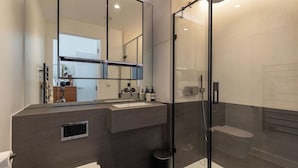 Une salle de bain moderne avec un grand miroir, une douche en verre et un meuble-lavabo.
