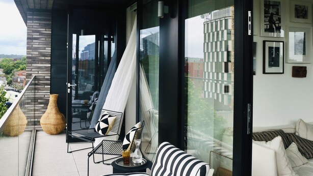 Un espace extérieur moderne avec un canapé rayé noir et blanc, une petite table avec une boisson et un vase décoratif.