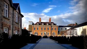 A long, straight pathway leading to a large, multi-story building with a symmetrical facade and a central entrance.