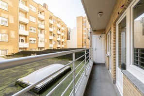 Ein Balkon mit Metallgeländer, der auf ein Gebäude mit zahlreichen Fenstern und Balkonen blickt.