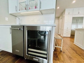 A modern kitchen with white cabinetry, a stainless steel oven, and a wooden floor.