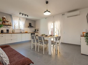 Eine moderne Küche mit weißen Schränken, einem Esstisch mit Stühlen und einem braunen Sofa.