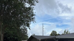 A backyard with a swimming pool, two lounge chairs, a wooden fence, and a small brick building. - Home in the heart of Fort Walton Beach with private pool, minutes fromthe beach (Fort Walton Beach)