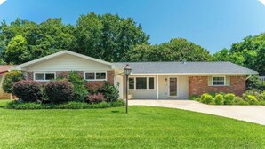 A single-story house with a brick facade, a front porch, and a well-maintained lawn. - Home in the heart of Fort Walton Beach with private pool, minutes fromthe beach (Fort Walton Beach)