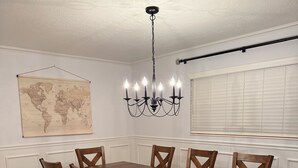 A dining room with a wooden table and chairs, a world map on the wall, and a chandelier. - Home in the heart of Fort Walton Beach with private pool, minutes fromthe beach (Fort Walton Beach)