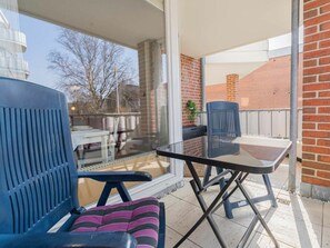 Ein Balkon mit Glastür, Tisch und zwei Stühlen.