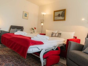 Ein Hotelzimmer mit einem Bett, einem Sessel, einem Nachttisch, einer Lampe und einem Bild an der Wand.