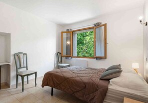 A bedroom with a bed, a chair, a desk, and a window with a view of greenery. - Riviera Countryside Family Villa (Le Bar-sur-Loup)