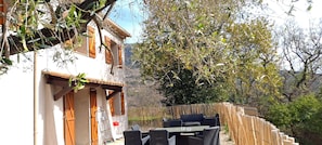 A white building with wooden shutters, a patio with wicker furniture, and a bamboo fence. - Riviera Countryside Family Villa (Le Bar-sur-Loup)