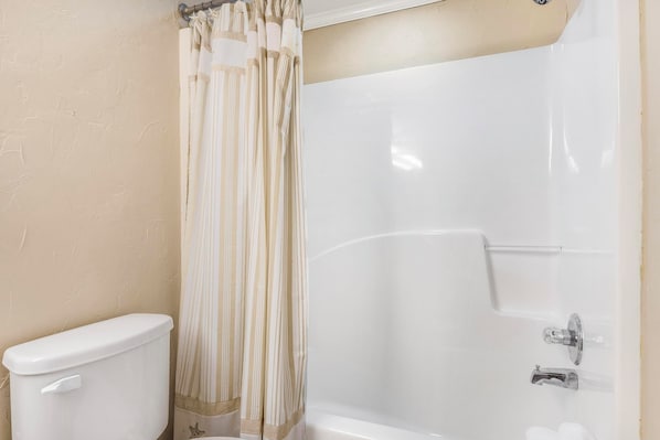 A bathroom with a toilet, a shower with a glass door, and a beige wall. - Romar Place 1105 🌊 Beachfront 3BR with Balcony + Pool (Orange Beach)