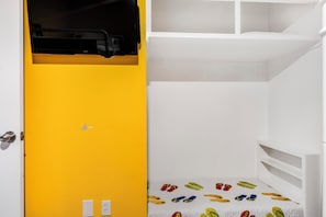 A room with a yellow door, a bunk bed with a colorful mattress, and a white wardrobe with a black object on top. - Romar Place 1105 🌊 Beachfront 3BR with Balcony + Pool (Orange Beach)