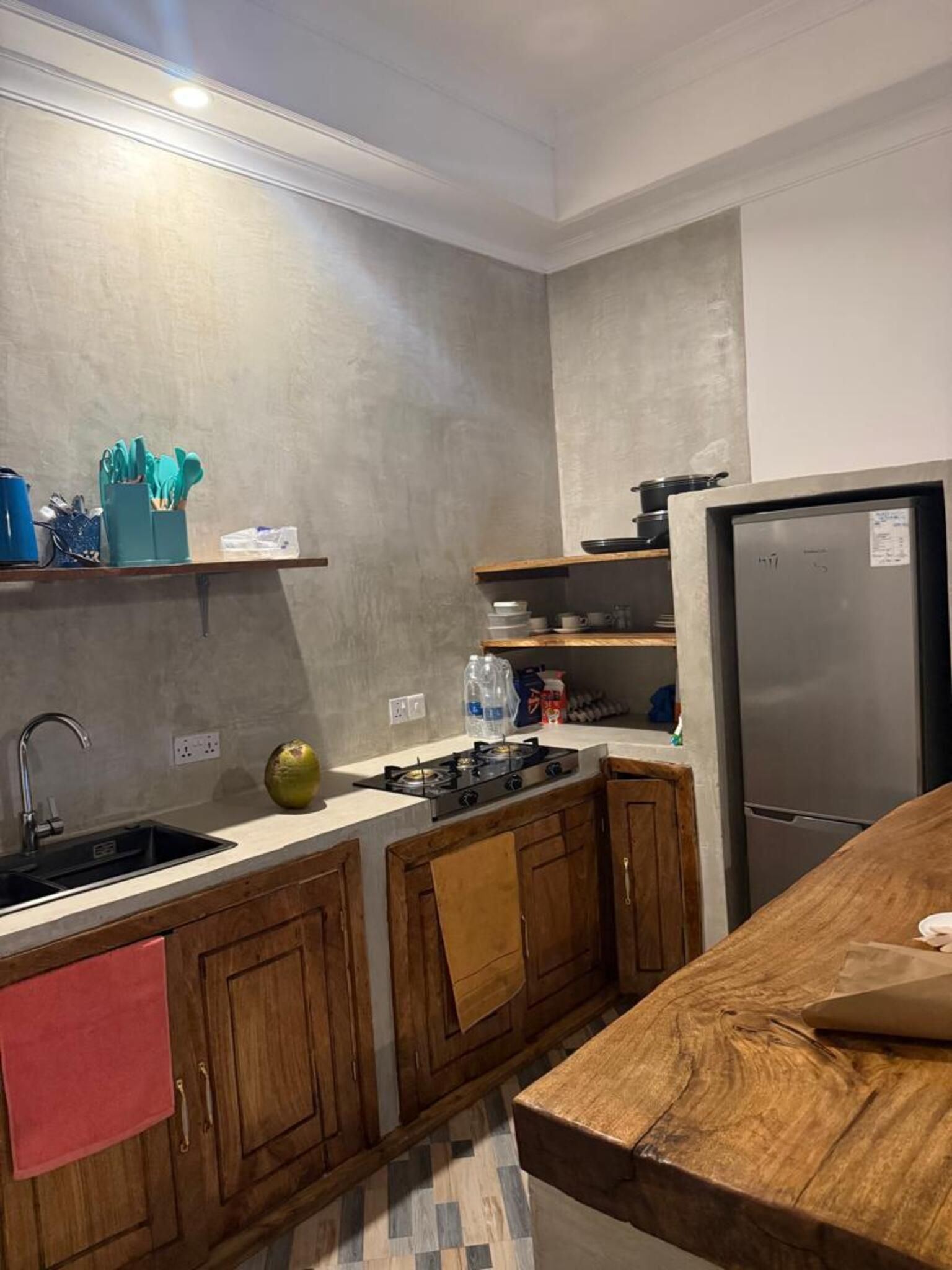 Cozinha moderna com geladeira de aço inoxidável, armários de madeira e painel de azulejos.