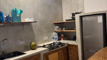 Cozinha moderna com geladeira de aço inoxidável, armários de madeira e painel de azulejos.