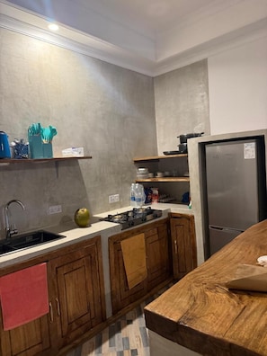 Cozinha moderna com geladeira de aço inoxidável, armários de madeira e painel de azulejos.