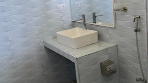 Un baño con un lavamanos blanco, un espejo y una ducha.