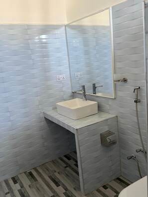 Uma casa de banho com uma pia branca, um espelho e um chuveiro.