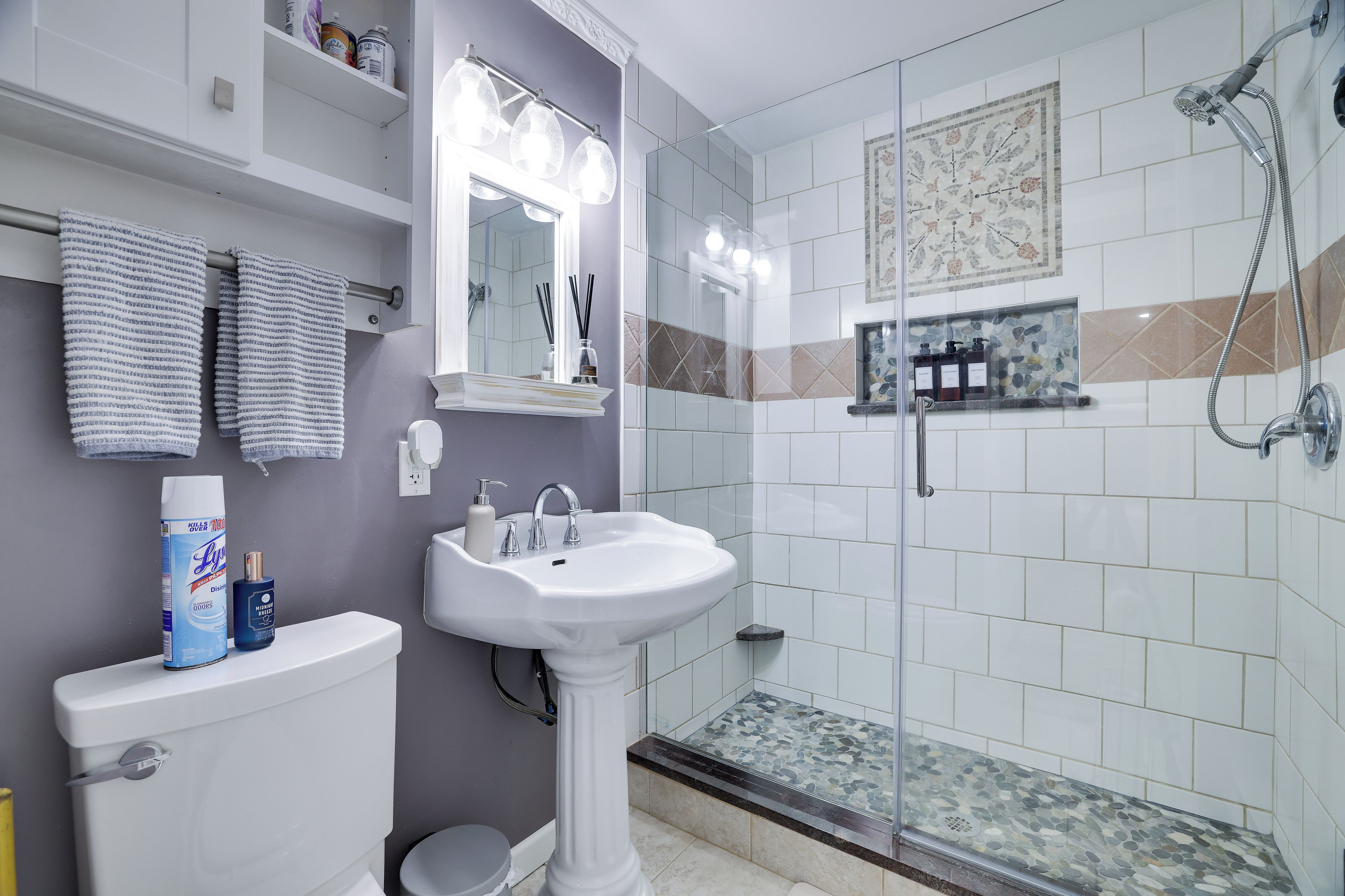 A bathroom with a pedestal sink, a toilet, a shower with glass doors, and a tiled shower floor.