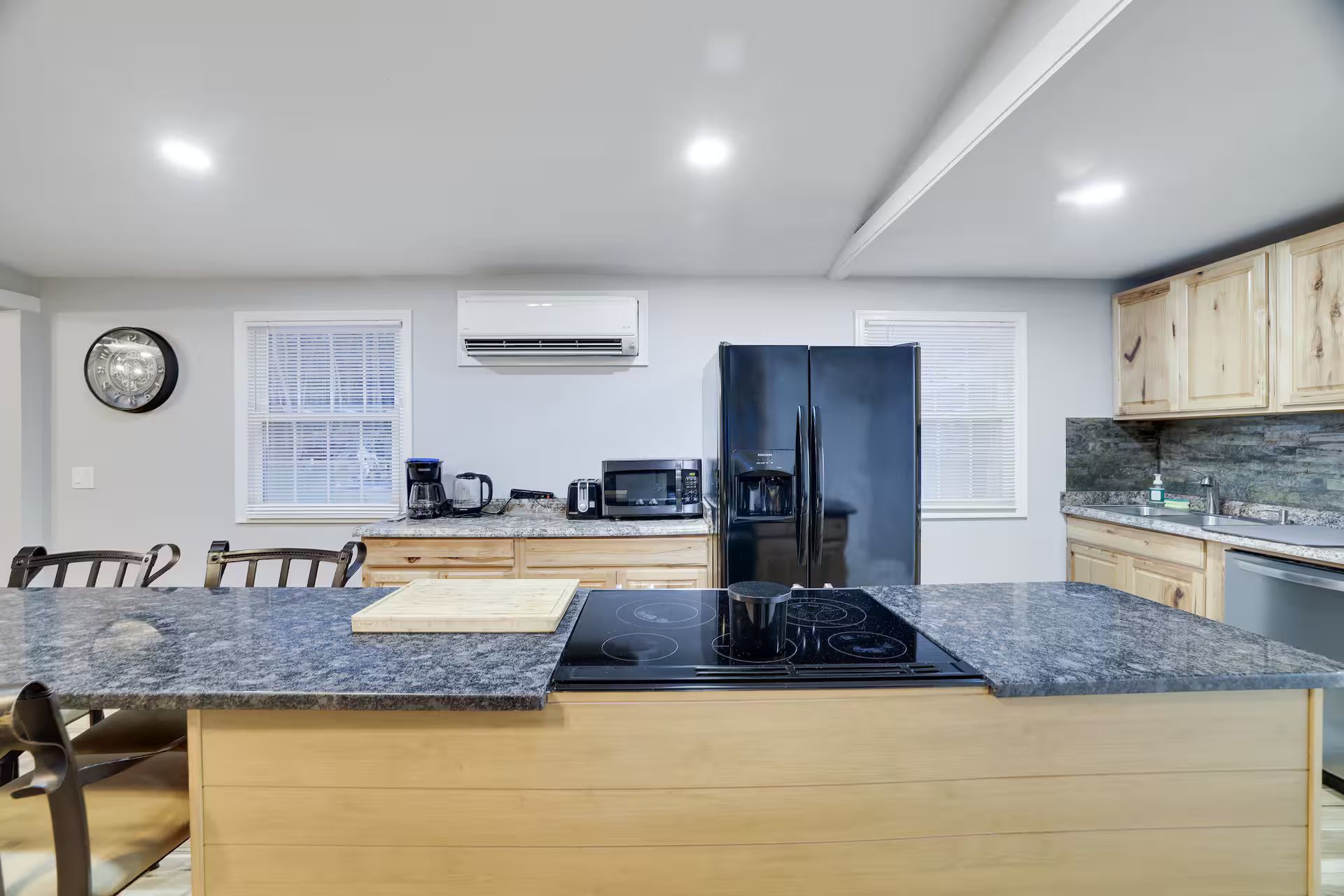 A modern kitchen with a central island, built-in appliances, and wooden cabinetry.