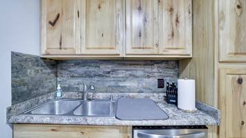 Una cocina con armarios de madera, encimera de granito, pileta doble y lavavajillas.