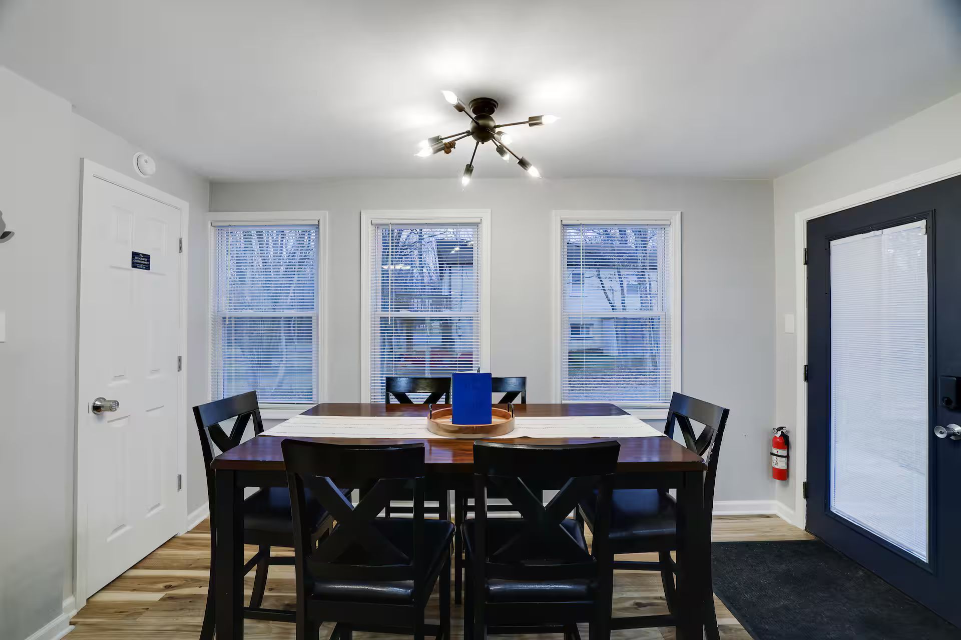 A dining area with a table and chairs, a ceiling fan, and a door with a sign.