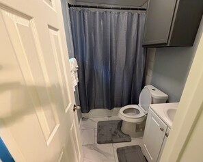 Ein kleines Badezimmer mit Toilette, Duschvorhang und Waschbecken.