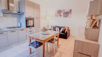 A modern kitchen with a dining area, a sofa, and a lamp.