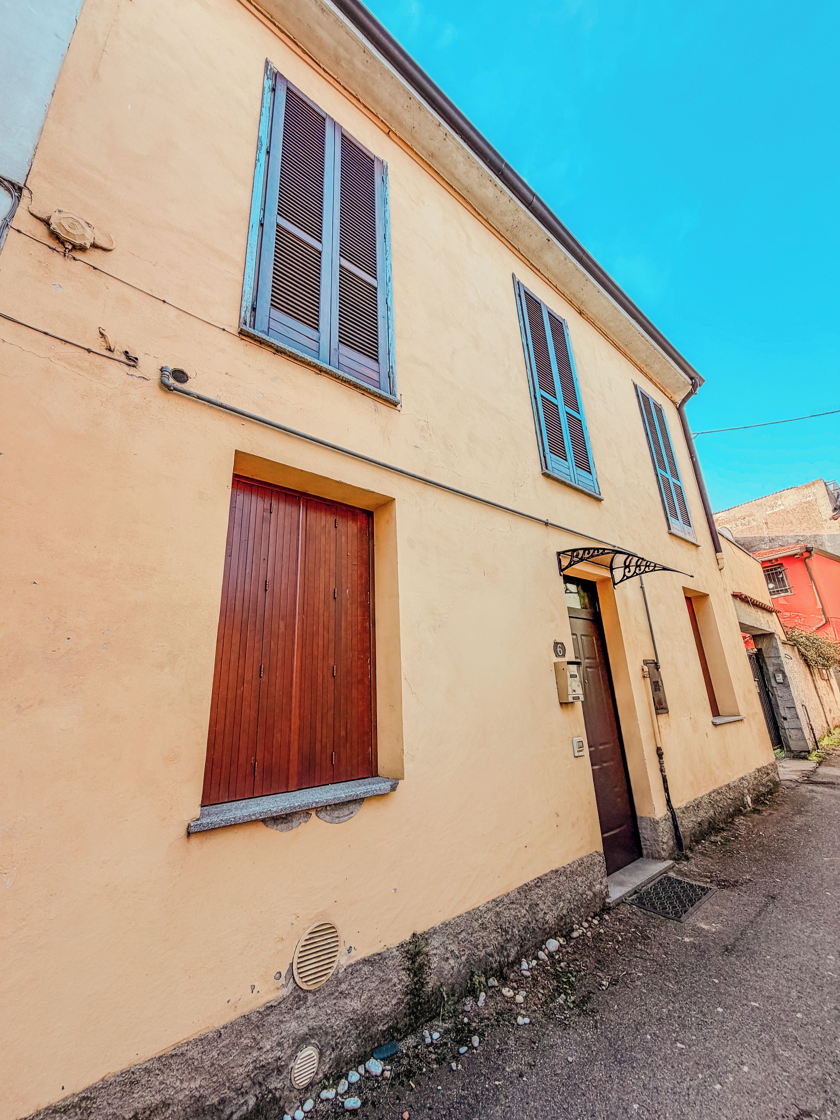 Un edificio a due piani con facciata beige, una porta in legno e una finestra con persiane.