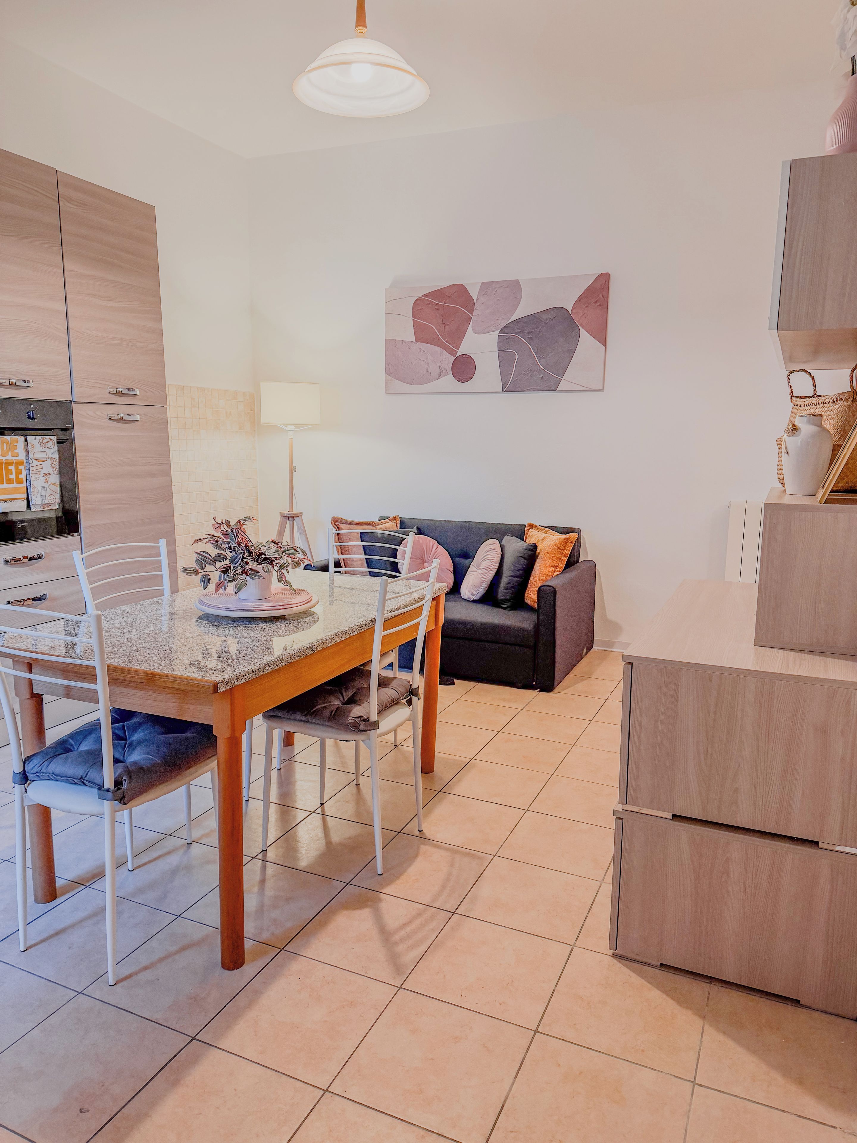 Una cucina moderna con zona pranzo, divano e un quadro appeso al muro.