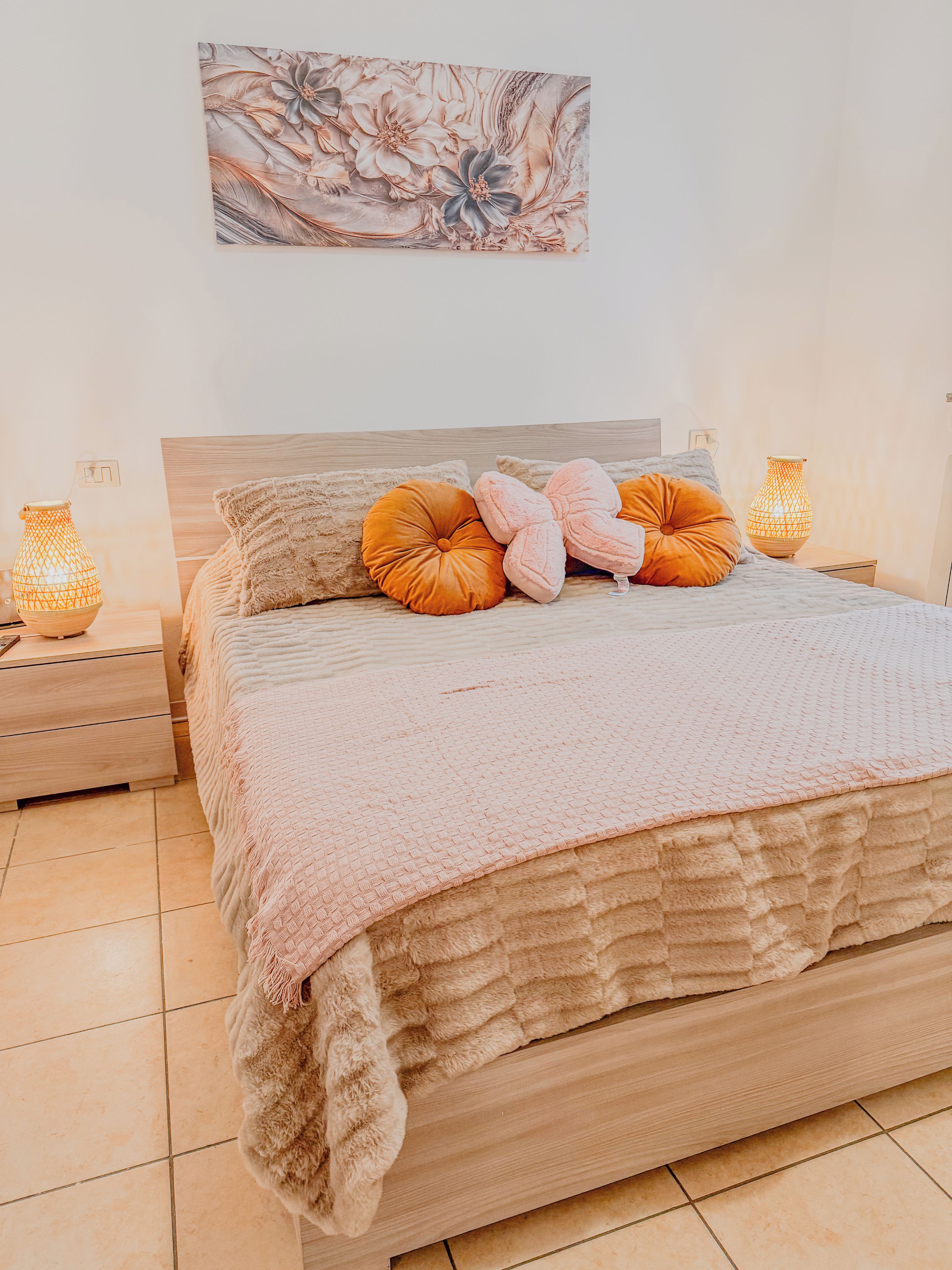 A bedroom with a large bed, two bedside tables, and a wall-mounted artwork.