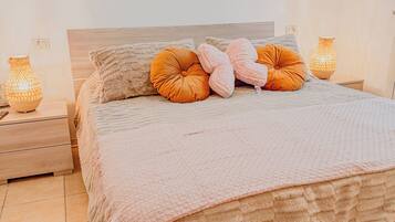 A bedroom with a large bed, two bedside tables, and a wall-mounted artwork.