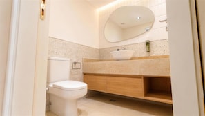 Ein modernes Badezimmer mit Toilette, Waschbecken und einem Holzkonsolenunterschrank.