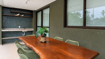 Un comedor con una mesa de madera, sillas verdes, una planta en maceta y un salpicadero de azulejos.