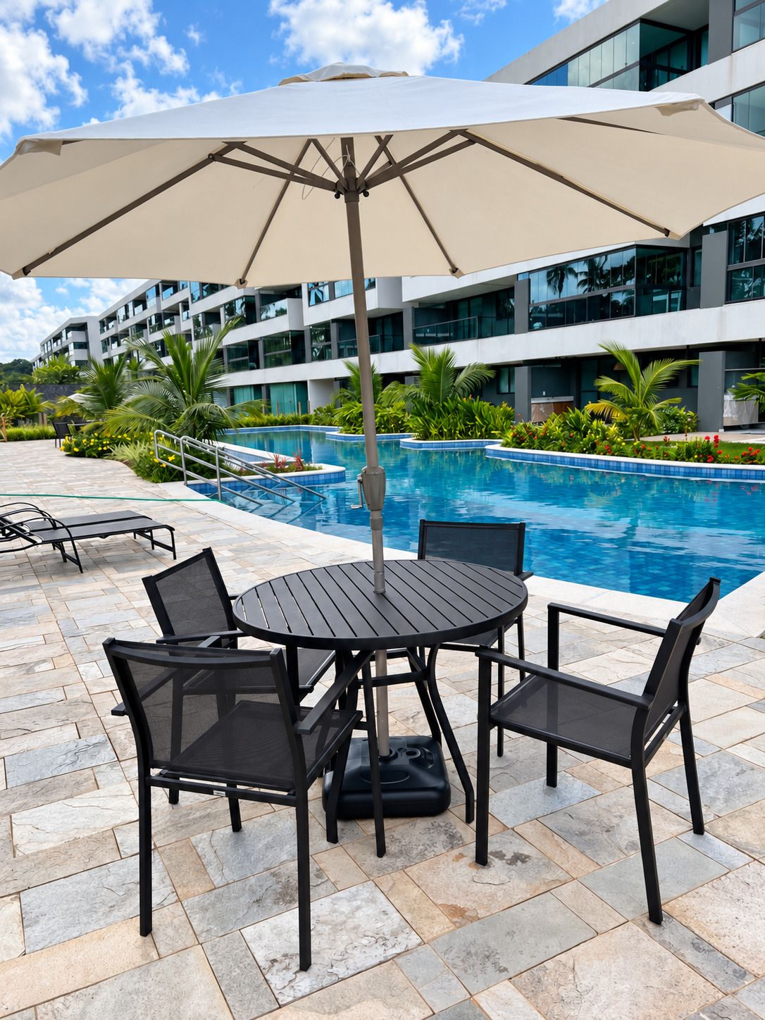 Zona junto a la piscina con mesa y sillas, una piscina y un edificio moderno al fondo.